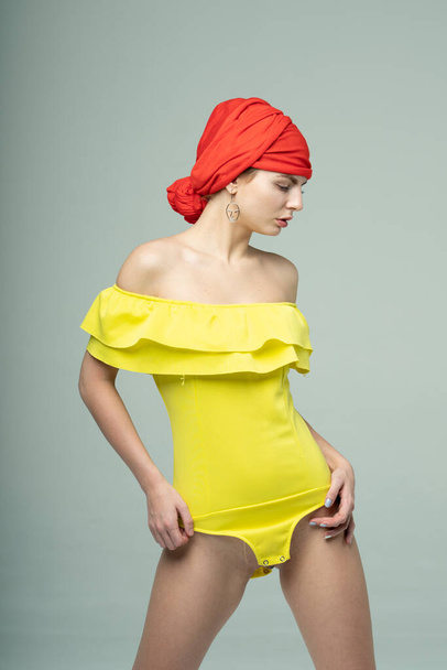 young beautiful girl posing in a yellow bodysuit - Фото, зображення
