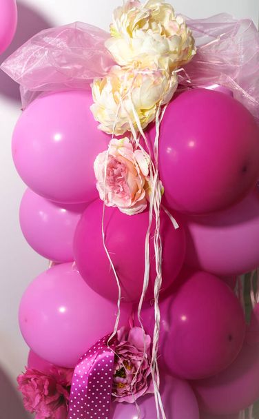 рожеві і червоні кульки пов'язані разом і прикрашені квітковими прикрасами і стрічками
 - Фото, зображення