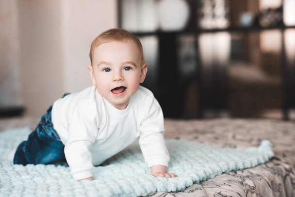 Cute baby boy wearing stylish clothes crawling in bed. Looking at camera. Childhood.  - Photo, Image