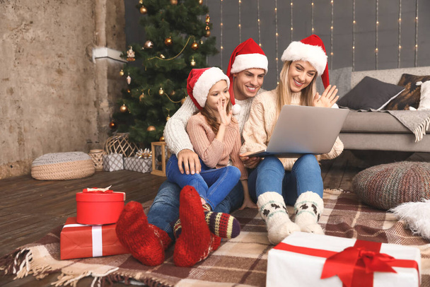 Счастливая семья с ноутбуком в канун Рождества дома
 - Фото, изображение