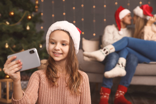 Klein meisje neemt selfie op kerstavond thuis - Foto, afbeelding