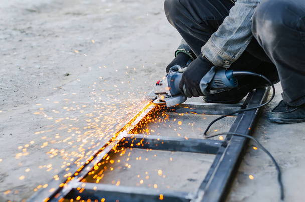 Metal cutting with an electric circular saw. Sparks fly in diffe - Foto, immagini