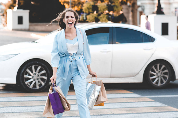 Mujer riendo de compras en la ciudad con ropa de casula elegante al aire libre. Mirando la cámara. Tiempo de venta
.  - Foto, imagen