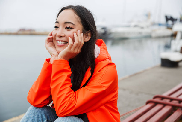 Smiling attractive young asian woman wearing raincoat - Foto, imagen