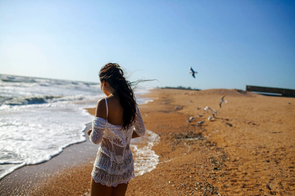 happy asian woman running on sandy beach between birds. - Photo, Image