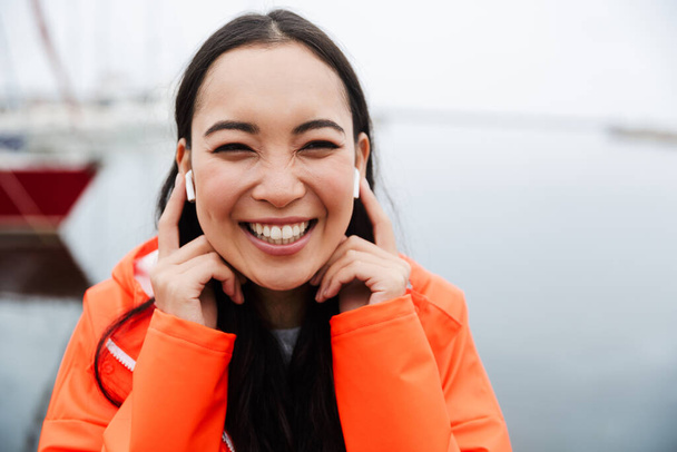 Sonriente atractivo joven asiático mujer usando impermeable
 - Foto, imagen