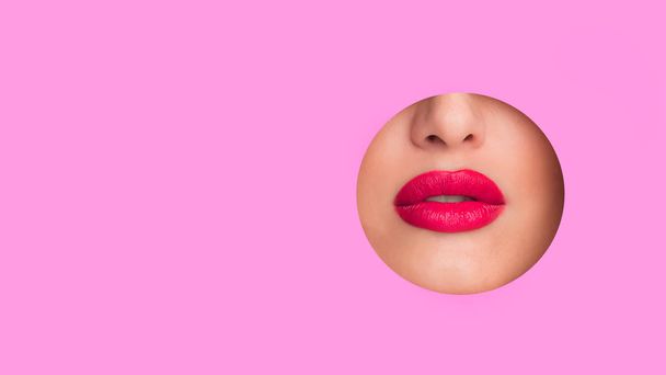 Woman showing red lips in round hole of pink paper - Foto, Imagen