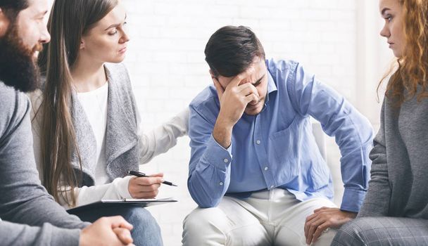 Depressed addicted man receiving support from group members at therapy session - Photo, Image