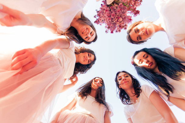 Happy young bridesmaids looking down together, bottom view - Foto, imagen