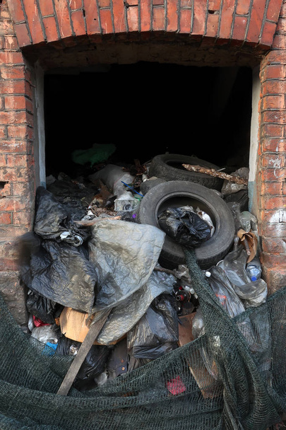 Ventana en una vieja casa de ladrillo llena de basura con neumáticos de coche
 - Foto, imagen