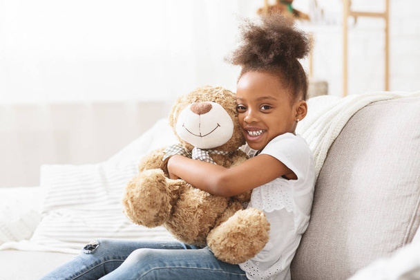 Happy black kid girl hugging teddy bear, posing at camera - Φωτογραφία, εικόνα