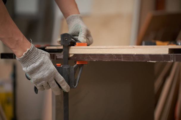 Male carpenter clamps board in vice in workshop - 写真・画像