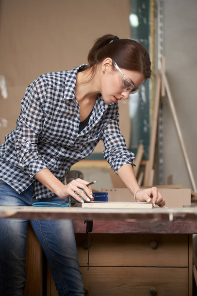 Woman carpenter in glasses with tape measure and blackboard - Foto, Bild