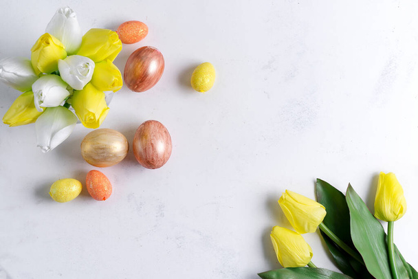 Επίπεδη Lay Golden Easter Αυγά με τουλίπες σε πέτρινο μαρμάρινο φόντο. Πασχαλινό φόντο ή έννοια Πάσχα. - Φωτογραφία, εικόνα