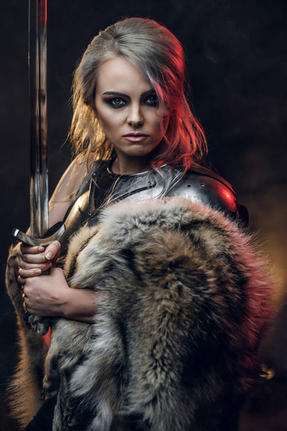 Ritratto di una bellissima guerriera con una spada che indossa corazza d'acciaio e pelliccia. Moda fantasy. Cosplayer come Ciri de La Strega
. - Foto, immagini