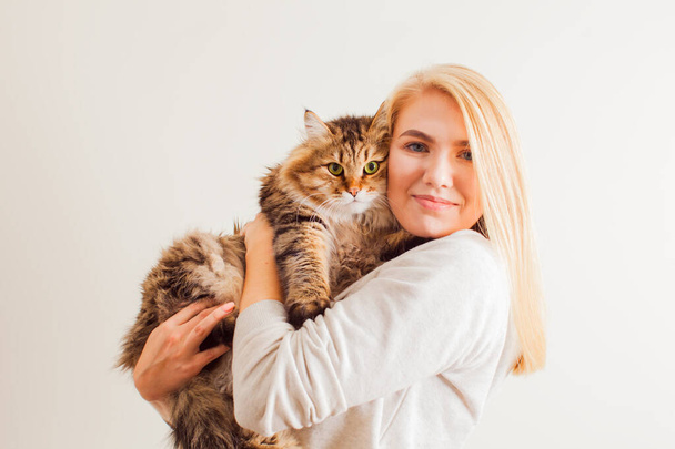 Beautiful woman holding new adopted fluffy cat with green eyes - Fotó, kép
