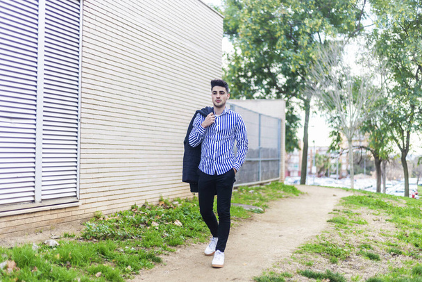 Young bearded man walking around in the city holding a jacket - Zdjęcie, obraz