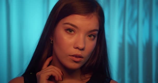Portrait young caucasian girl blue background curtain neon light sensuality temptation - Πλάνα, βίντεο