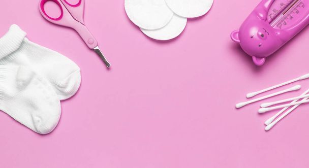 Baby rosa Schere für Maniküre, Thermometer, Watteschwämme Tupfer Knospen, weiße Socken auf rosa Hintergrund von oben flach liegend. Kosmetische Accessoires für Kinderhygiene. Babypflegekonzept - Foto, Bild