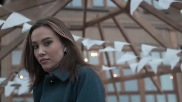 junges asiatisches hübsches Mädchen im blauen Mantel, Rollkragen mit welligem Haar blickt in die Kamera - Filmmaterial, Video