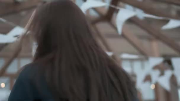 νεαρή ασιατική όμορφη κοπέλα σε μπλε παλτό, ζιβάγκο με κυματιστά μαλλιά κοιτάζει κάμερα - Πλάνα, βίντεο