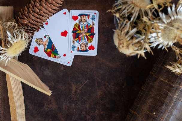 Valentine's day, playing cards with pine cone, kindling on leather background. - Photo, Image