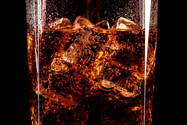 黒の背景に隔離された氷のキューブと液滴を持つコーラガラス  - 写真・画像