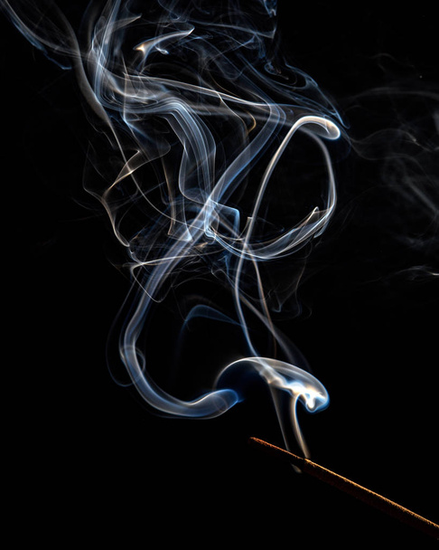 A trickle of white smoke from an incense stick on a black background - Foto, immagini