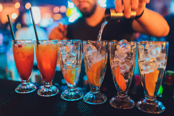 Il barista fa versare il cocktail in un bicchiere in piedi sul bancone
. - Foto, immagini