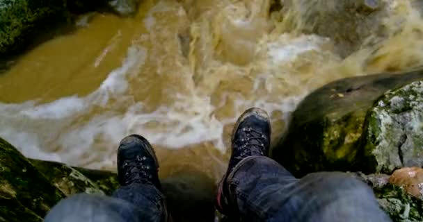 Túrázó lóg a lábát a folyó felett a szikláról - Felvétel, videó