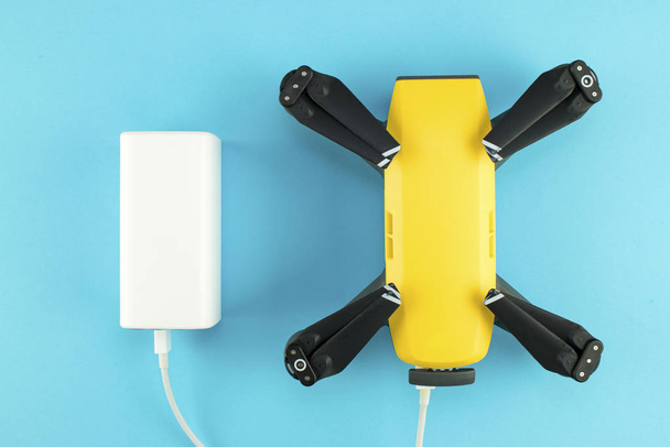 The quadrocopter is charged from a powerbank via a cable. - Foto, Imagem