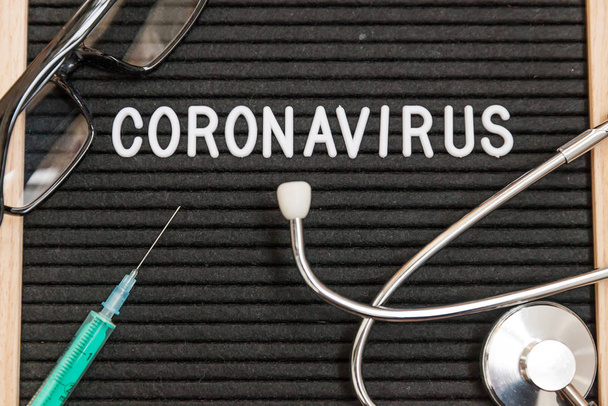 Κείμενο φράση Coronavirus σύριγγα και στηθοσκόπιο σε μαύρο φόντο πίνακα γραμμάτων. Novel coronavirus 2019-ncov, Mers-Cov αναπνευστικό σύνδρομο Μέσης Ανατολής coronavirus καταγωγής Κίνας Wuhan - Φωτογραφία, εικόνα