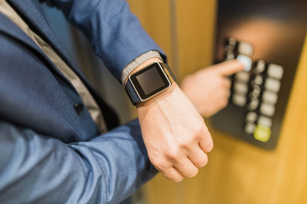 Man with smartwatch on his hand using elevator control panel. - Fotoğraf, Görsel
