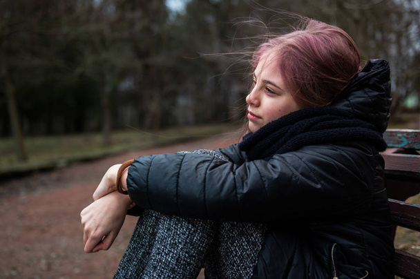 traurig depressives junges Mädchen sitzt auf einer Bank in einem Park - Foto, Bild