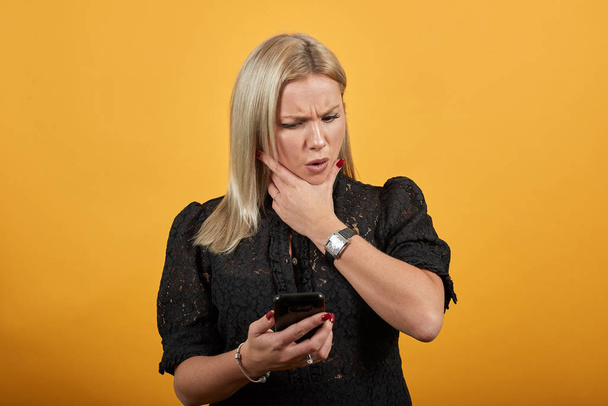 девушка в черном платье недовольная женщина смотрит и раздражается на телефон
 - Фото, изображение