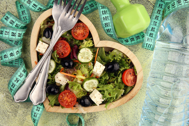Authentic fresh salad in a wooden heart shaped cup with dumbbell - Photo, Image