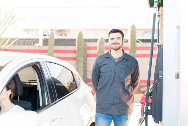 Confident male attendant standing by fuel pump at gas station - Φωτογραφία, εικόνα