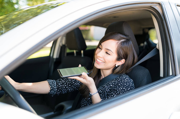 lächelnde erwachsene Frau, die im Auto auf dem Smartphone spricht - Foto, Bild