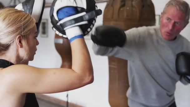 Senior male boxer with younger female coach in gym using training gloves - shot in slow motion - Materiał filmowy, wideo