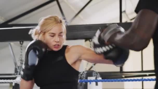 Male boxing coach with female boxer in gym using training gloves in boxing ring - shot in slow motion - Filmati, video