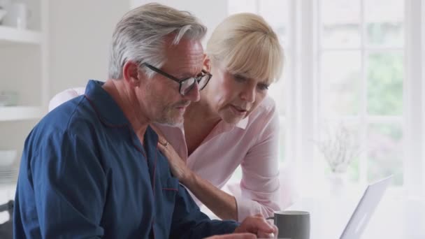 Senior couple with man in wheelchair at home holding packet of pills looking up information about side effects online using laptop - shot in slow motion - Filmmaterial, Video