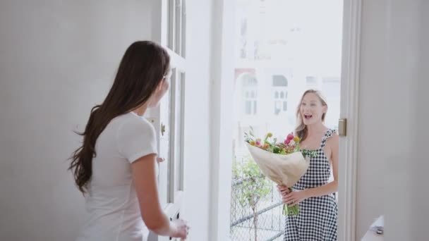 Woman opening front door to gay female partner who gives her a bunch of flowers - shot in slow motion - Metraje, vídeo