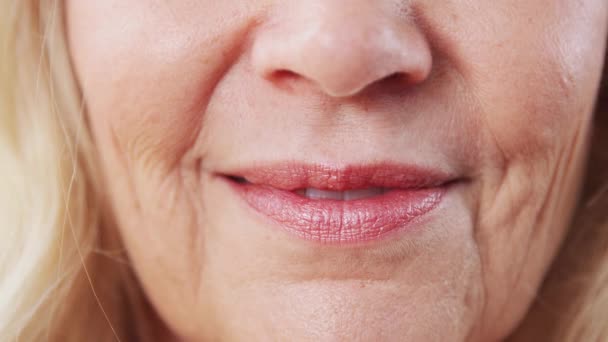 Close up studio shot of mature womans mouth as she smiles at camera - shot in slow motion - Felvétel, videó