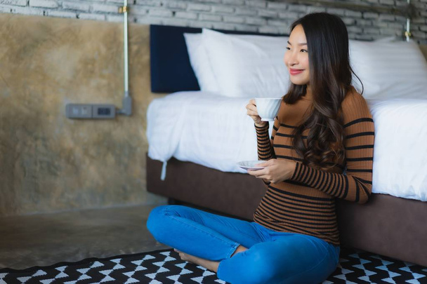 Young asian woman with coffee cup on bed - Foto, Bild