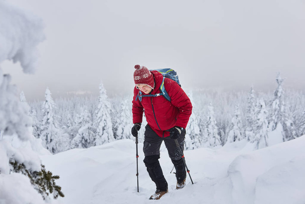 férfi utazó mászik egy hegyet hóesés közben - Fotó, kép