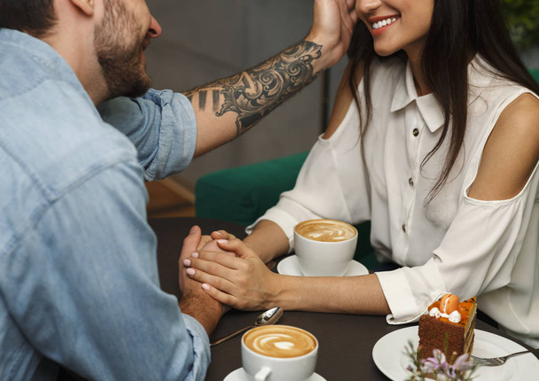 Chłopak dotykanie dziewczyny włosy o romantyczną randkę w kawiarni, przycięte - Zdjęcie, obraz
