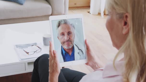 Mature woman having online medical consultation with doctor at home using digital tablet - shot in slow motion - Felvétel, videó