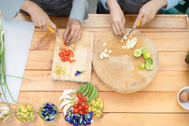Δύο Ασιάτισσες έκοψαν σκόρδο και ντομάτα με μαχαίρι στο αγριογούρουνο - Φωτογραφία, εικόνα