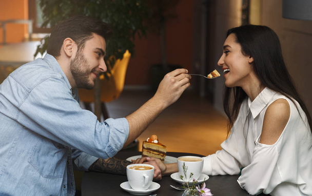 Любовники кормят друг друга, имея свидание в кафе
 - Фото, изображение