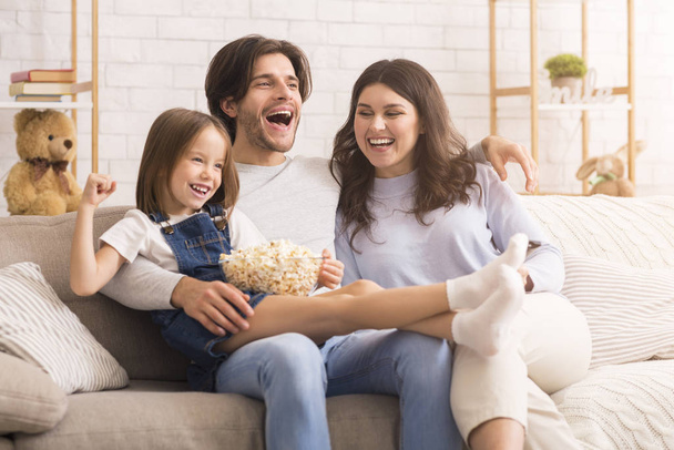 Bambina guardando commedia film con mamma e papà a casa
 - Foto, immagini